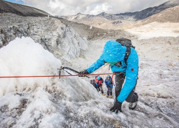 Hikers climbing an icy rock face